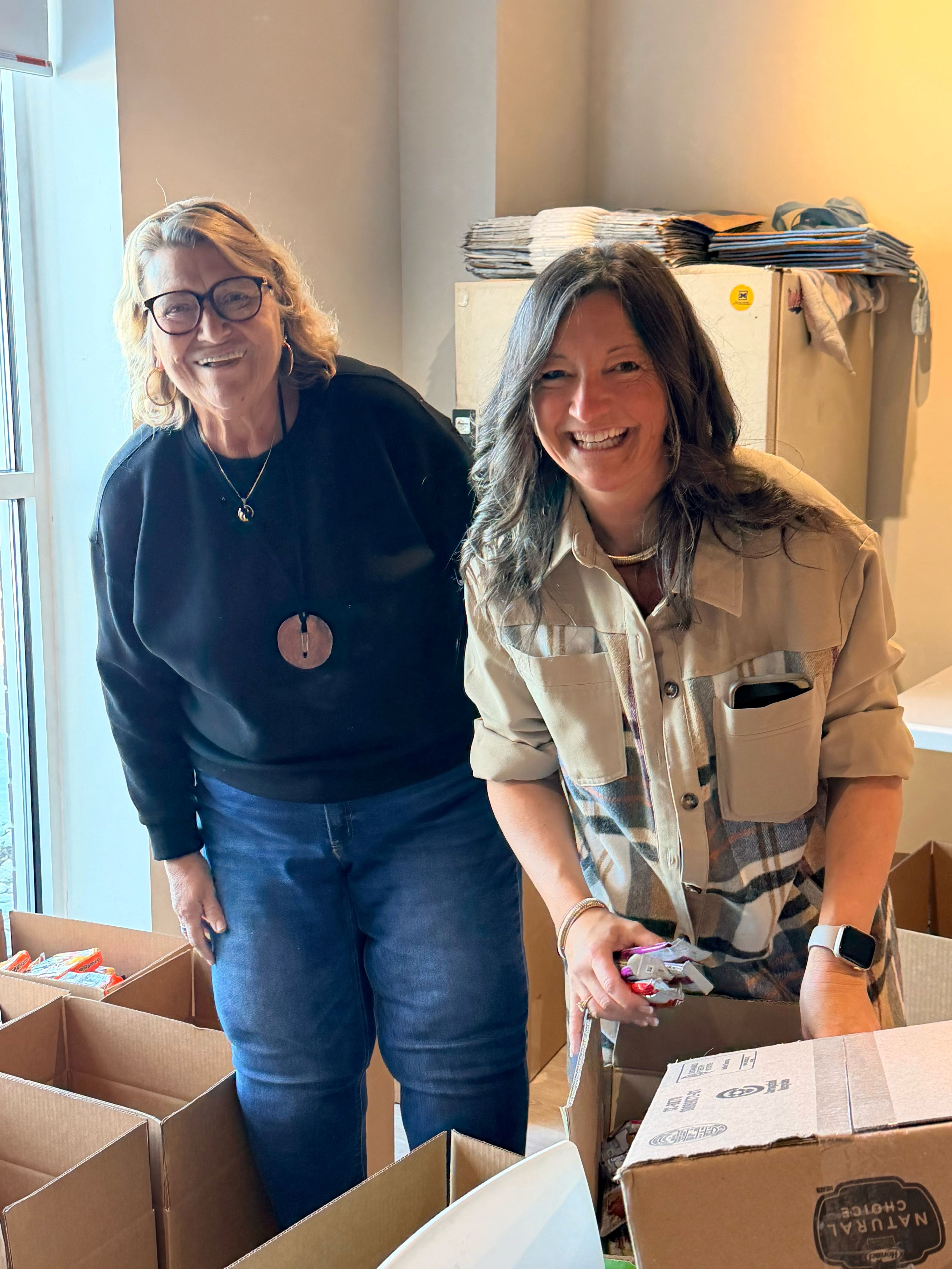 United Way Board Members Dee Custar(L) and Misty King(R) help fill boxes for those in need